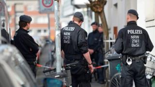 Police stand outside the building where the attacker reportedly lived