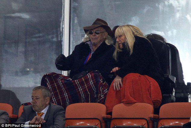 Owner Owen Oyston watches the match huddled under a blanket in the stands