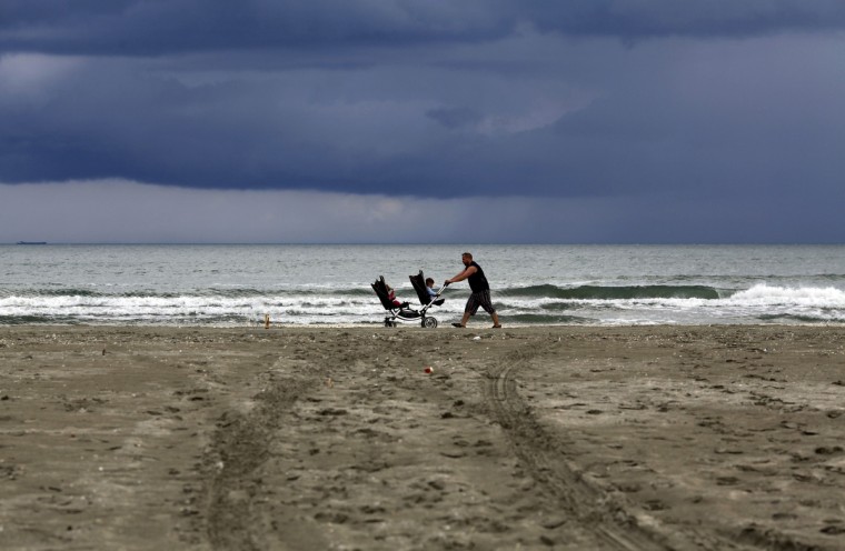 A man pushes a pram with two children by the Black Sea beach after a heavy rain in Navodari, Romania. (Radu Sigheti/Reuters)