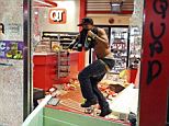 A man leaves a store on Sunday, Aug. 10, 2014, in Ferguson, Mo. A few thousand people crammed a suburban St. Louis street Sunday night at a vigil for unarmed 18-year-old Michael Brown shot and killed by a police officer, while afterward several car windows were smashed and stores were looted as people carried away armloads of goods as witnessed by an an Associated Press reporter. (AP Photo/St. Louis Post-Dispatch, David Carson)