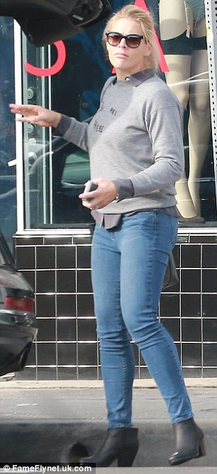 Casual style: The mother-of-two wore a dark grey collared shirt under her pullover and completed her outfit with faded skinny denim jeans and black ankle booties