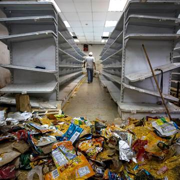 Image: A man walks down the aisle of a destroyed grocery store 