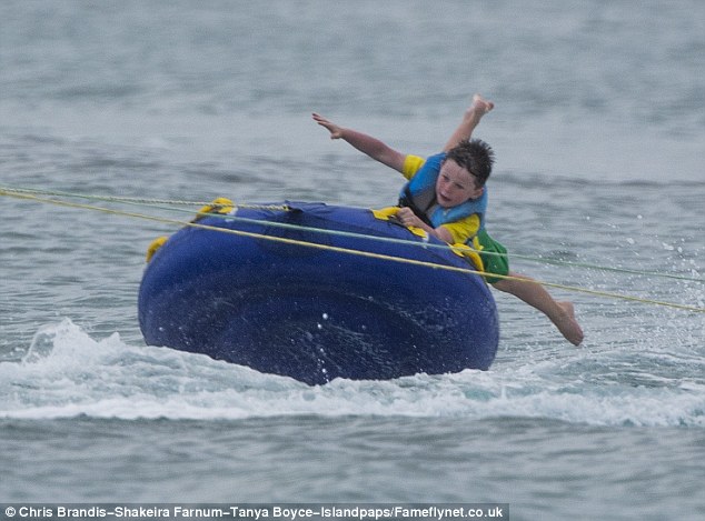 Having a great time: Kai had lots of fun in the water and was pictured holding on tightly as he was pulled along on an inflatable