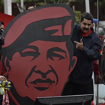 Image: President Nicolas Maduro stands next to a placard depicting late leader Hugo Chavez