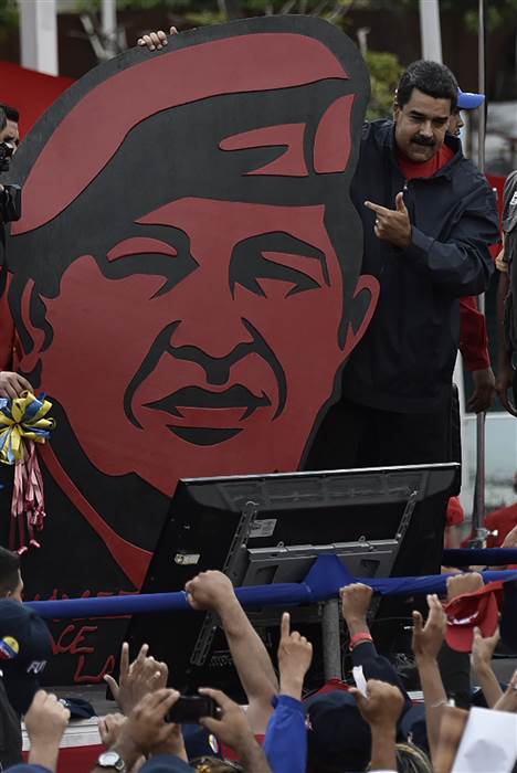 Image: President Nicolas Maduro stands next to a placard depicting late leader Hugo Chavez