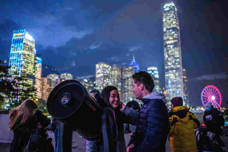 People set up telescopes near Victoria Harbour in hopes of seeing a supermoon on a cloudy evening in Hong Kong.