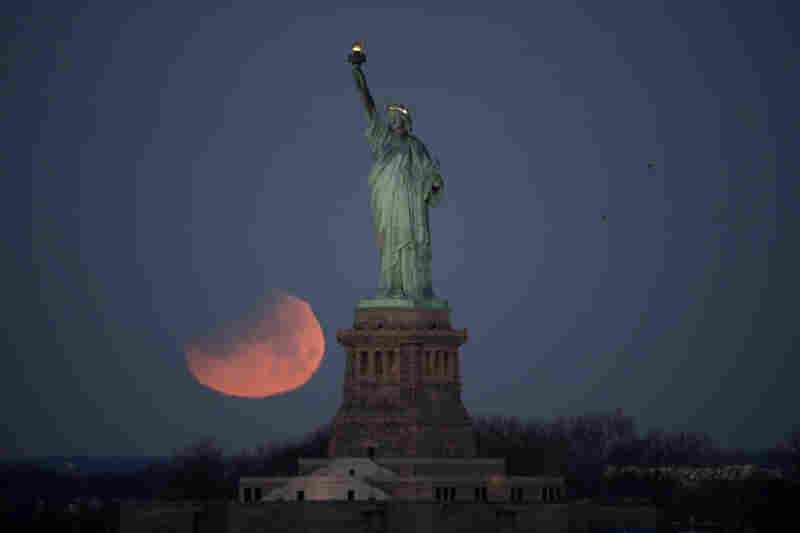 The Statue of Liberty is backdropped by a supermoon on Wednesday as seen from Brooklyn. The supermoon, which is the final of three consecutive supermoons, also experienced lunar eclipse as it set over the horizon, but only a partial eclipse was visible on the East Coast.