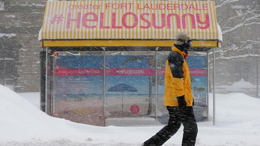 A pedestrian walks past a bus stop with an advertisement for Florida during a winter blizzard in Boston, Massachusetts.