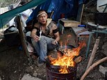 A man cooks a meal over a make-shift fire in the jungle camp which is home to several hundred of San Jose's homeless is just miles from the booming Silicon Valley