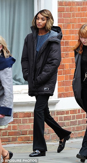 Early start: The model kept warm with a large black jacket in between takes before posing for more photos in a sequinned top and black skinny jeans