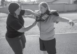 GEARING UPmdash;Victoria Anderson-Ornsbey, left, helps fit shoulder pads on Ventura County Wolfpack teammate Megan Evans. Anderson-Ornsbey is an Oak Park High graduate. The Wolfpack, in its first season of operation, does not have a home field yet for the upcoming season. The team was denied a home field by the Oxnard Unified High School District, but players are waiting to hear back from Newbury Park High. 