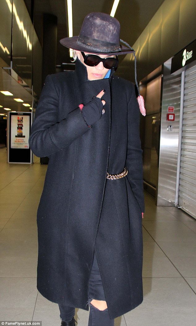 Keeping covered up: Ora held her coat shut as she strutted through the airport