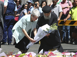 People lay flowers to pay respect to the shooting victims at a makeshift memorial at Martin Place in Sydney's Martin Place, Sydney Australia. Tuesday  Dec. 16,  2014. Three people including a lone gunman who took siege in a Sydney CBD cafe are dead after a police action ended in the early hours of the morning. (AP/Photo/Steve Christo)