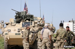 FILE - Kurdish fighters from the People's Protection Units (YPG) chat with members of U.S. forces in the town of Darbasiya next to the Turkish border, Syria, April 29, 2017.