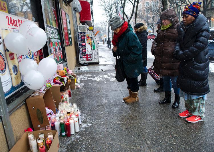 Passersby stop to pay their respects at a memorial to the fire victims at the corner of Prospect Ave. and E. 187th St. on Saturday.