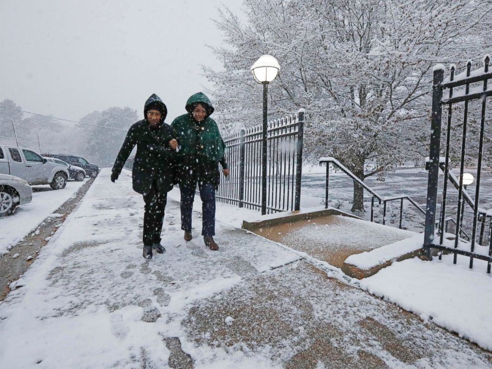 Worshippers link arms to avoid slipping as they walk along a snow-covered walkway to St. Richard Catholic Church to attend morning services, Friday, Dec. 8, 2017, in Jackson, Miss. The forecast called for a wintry mix of precipitation across several 