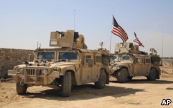 FILE - U.S. forces take up positions on the outskirts of the Syrian town of Manbij, March 7, 2017.