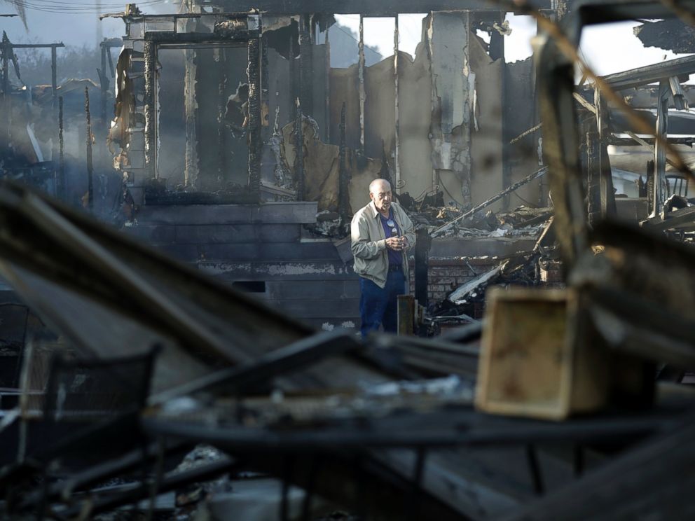 Dick Marsala looks through debris from his destroyed home after a wildfire roared through the Rancho Monserate Country Club Friday, Dec. 8, 2017, in Bonsall, Calif. The wind-swept blazes have forced tens of thousands of evacuations and destroyed doze