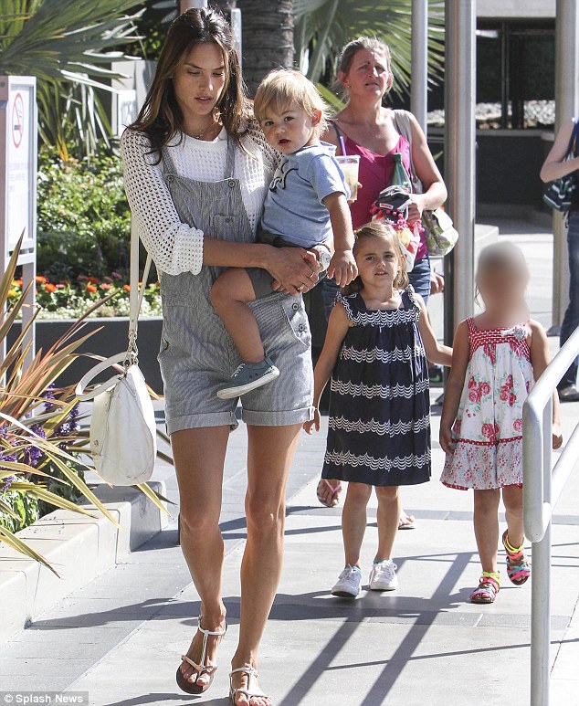 School run: Alessandra Ambrosia showed off her deliciously shapely legs in a pair of short dungarees as she carried her son Noah while picking up daughter Anja from school in Santa Monica on Friday