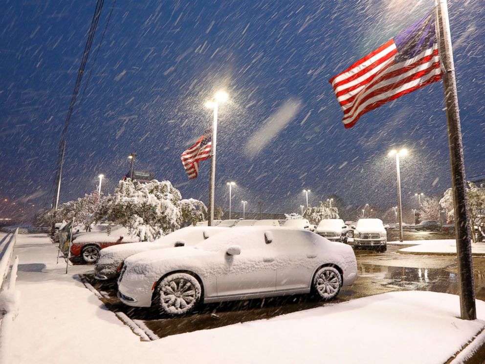 American flags wave as snow falls, blanketing vehicles in a car sales lot, Friday, Dec. 8, 2017, in Jackson, Miss. The forecast called for a wintry mix of precipitation across several Deep South states. (AP Photo/Rogelio V. Solis)