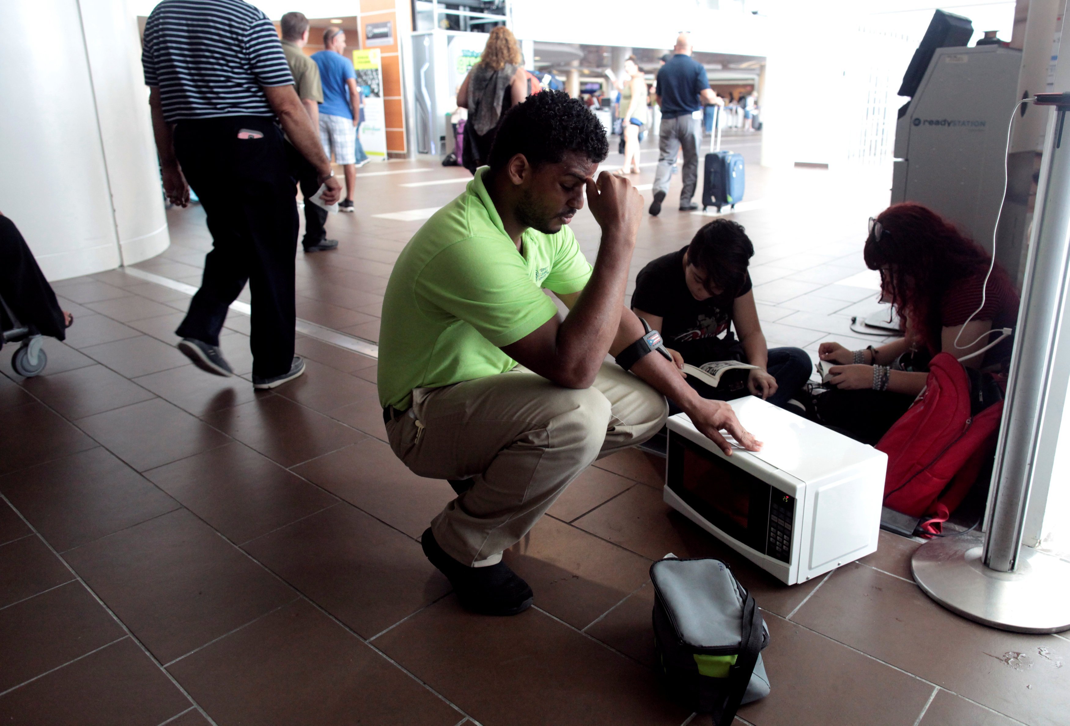 A man warms up his food in a microwave at Luis Muñoz Marín International Airport, where there is no air conditioning and only one food-and-beverage concession is operating.