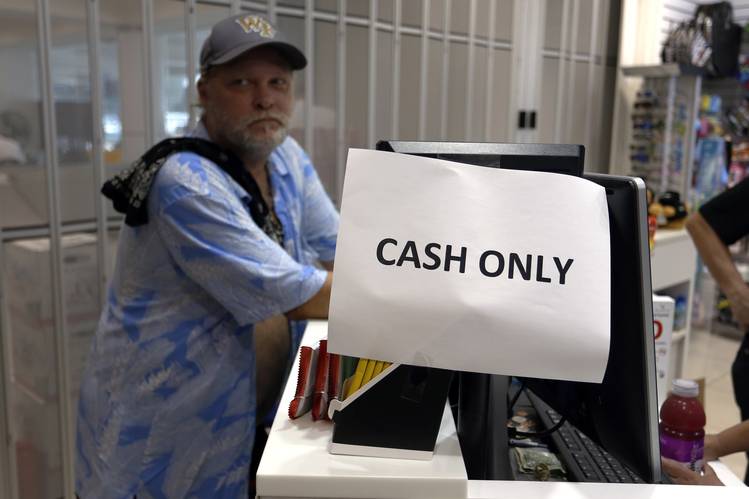 A worker at Luis Muñoz Marín International Airport stands next to a till that was unable to process credit card transactions on Monday. The airport’s operator said it expects the process of restoring to full service to take weeks.