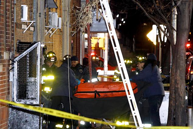 Fire officials and workers from the Medical Examiner's Office remove a body from the apartment building at 2363 Prospect Ave. in the Bronx early Friday morning after a fast-moving, 5-alarm fire killed 12 people.