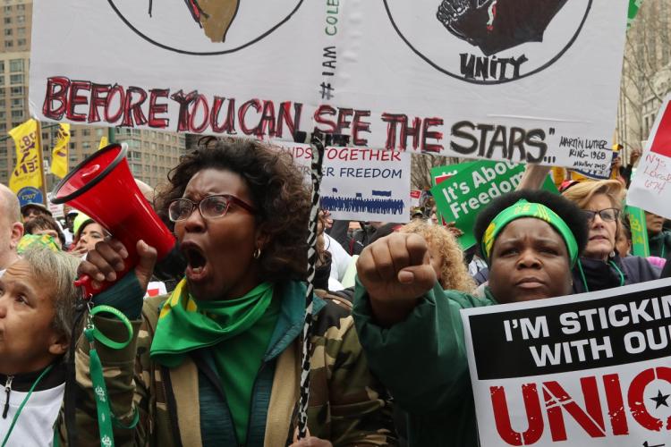 Workers hold up signs during the Working People's Day of Action in New York City Saturday in Foley Square.